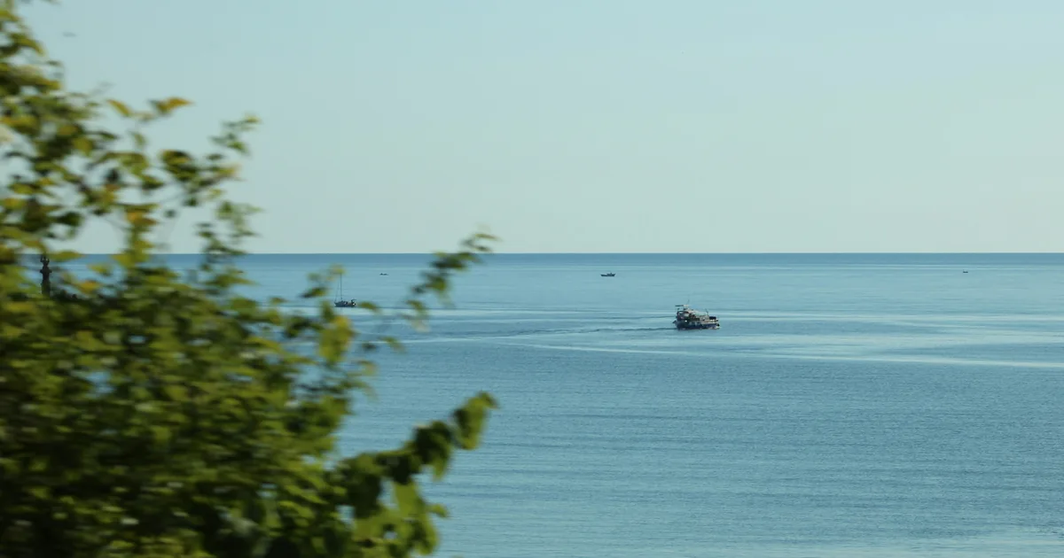 Лодка в спокойно море, погледната от брега
